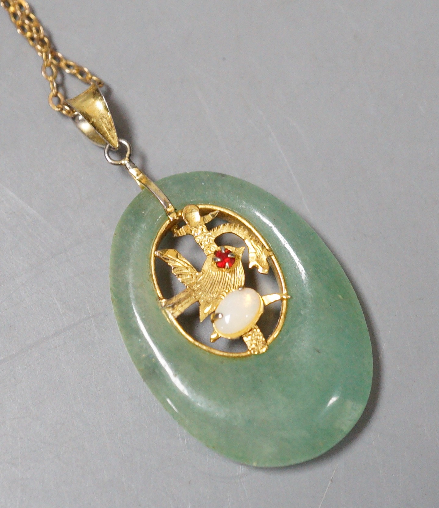 A gilt metal and gem set mounted oval adventurine quartz? pendant, 36mm, on a 9ct chain, 46cm, gross weight 9.4 grams.
